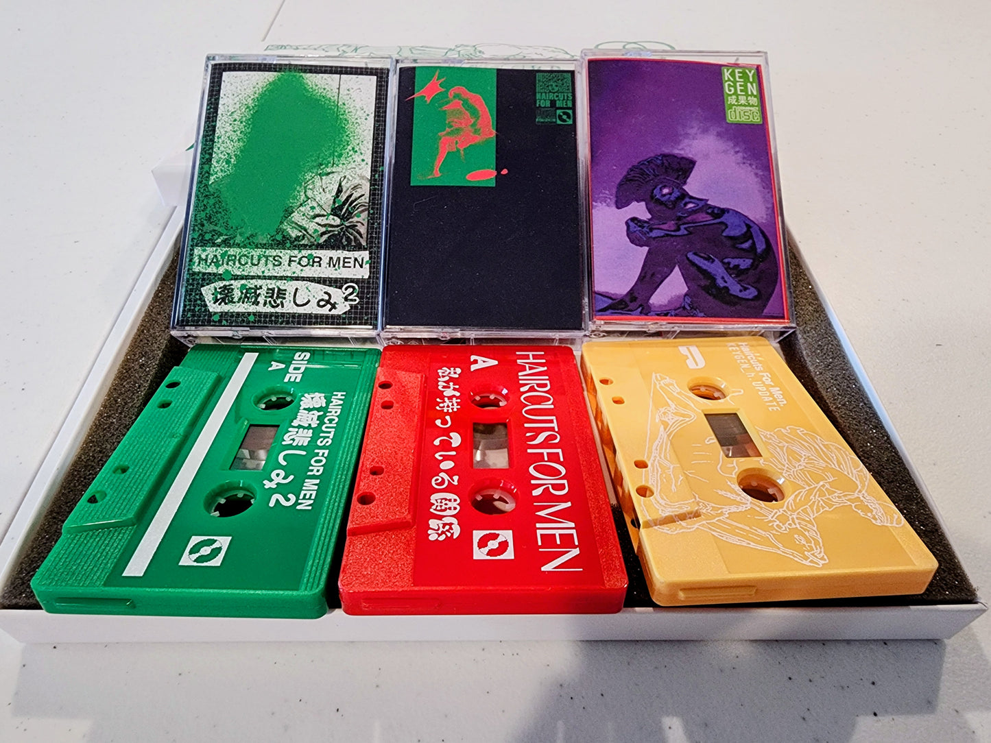 Collection of colorful cassette tapes in a box on a white surface